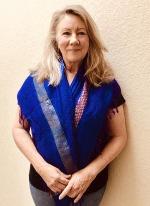 A woman in blue and black standing next to a wall.