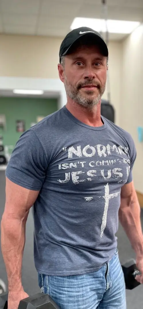 A man wearing a t-shirt with the words " norman isn 't coming to jesus ".