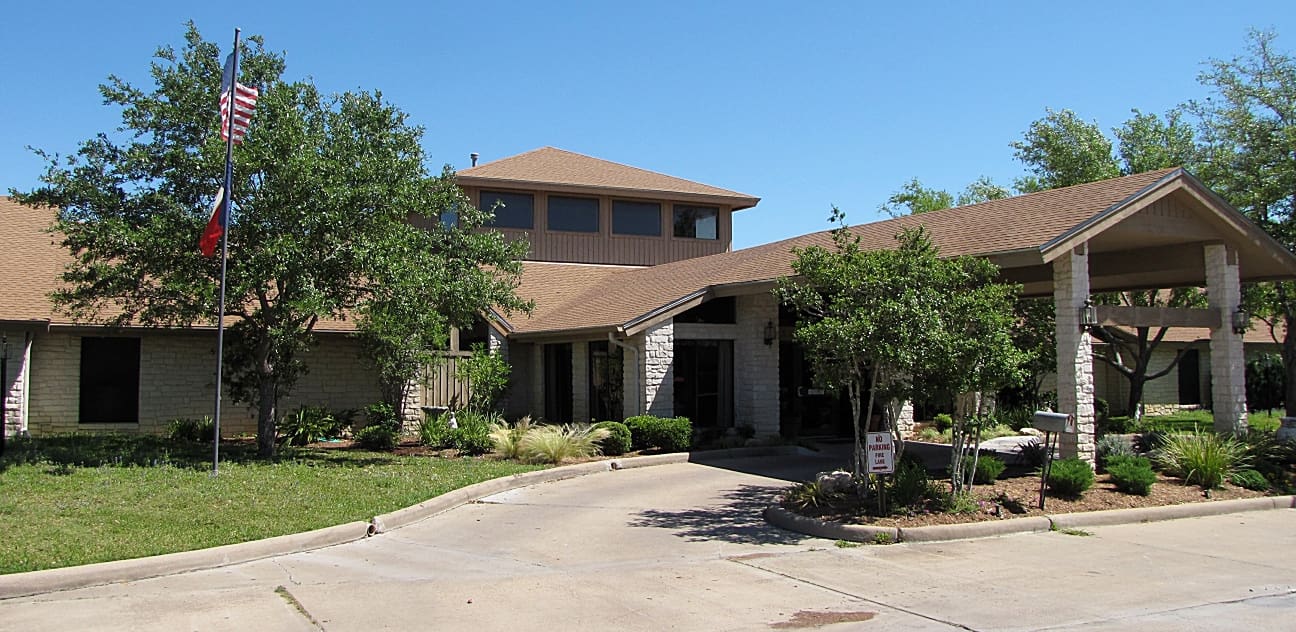 A large brown house with trees in front of it.